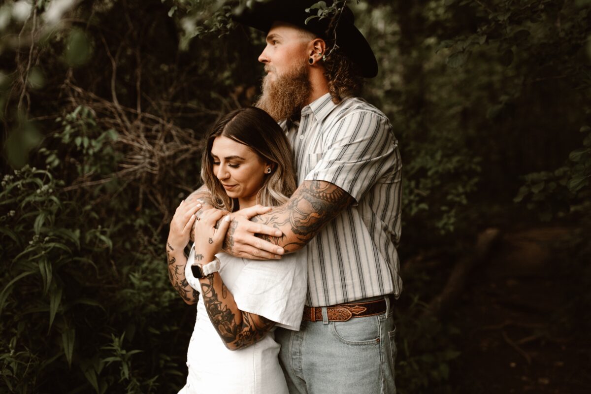 engaged tattooed couple embracing in the forest in the niagara region