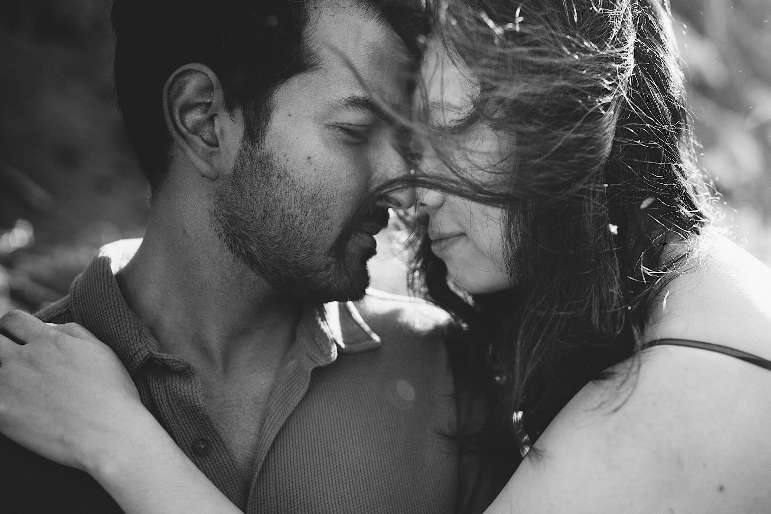 black and white engaged couple at the beach on a windy day