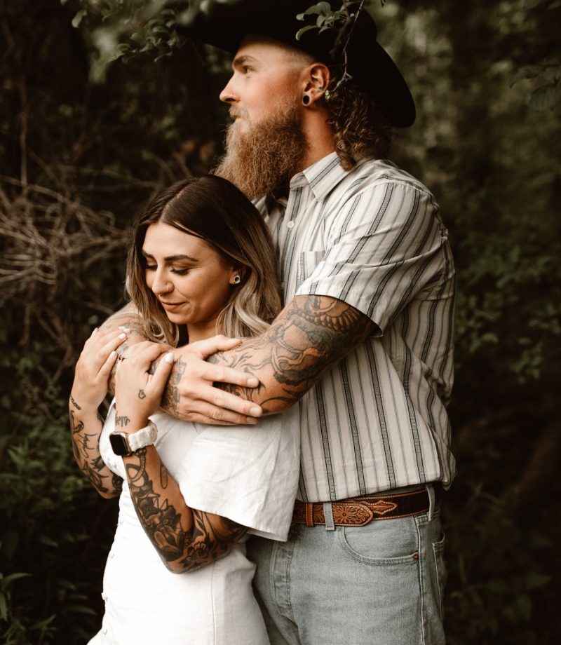 engaged tattooed couple embracing in the forest in the niagara region