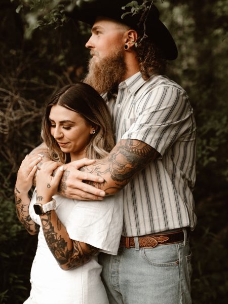 engaged tattooed couple embracing in the forest in the niagara region