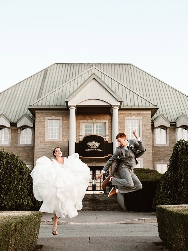 bride and groom jumping in front of chateau des charmes winery