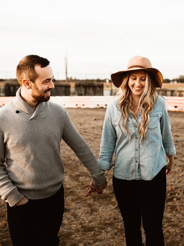 engaged couple walking and holding hands at merritville speedway